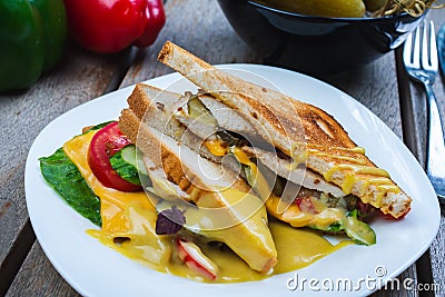 Classic breakfast, hot sandwiches with cheese, vegetables and chicken on a wooden table. Stock Photo