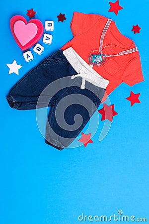 Classic children`s clothing on a blue background. Baby clothes collage. The boy is wearing a red shirt and jeans. pacifier and to Stock Photo