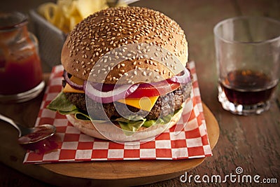 Classic deluxe cheeseburger with lettuce, onions, tomato and pickles on a sesame seed bun Stock Photo