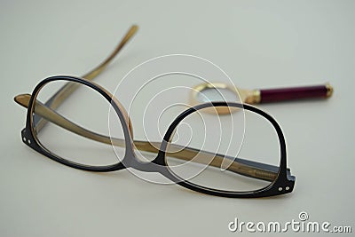 Classic eyeglasses with magnifying glass behind Stock Photo