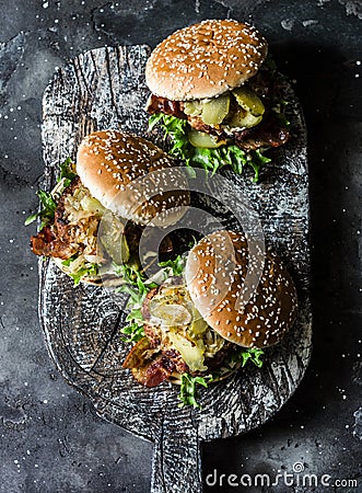 Classic homemade burger with pork cutlet, bacon, pickles, fried onions and mayonnaise mustard sauce on wooden chopping board, on Stock Photo