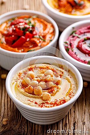 Classic hummus with olive oil and chickpeas sprinkled with paprika powder in a ceramic bowl on a wooden table Stock Photo