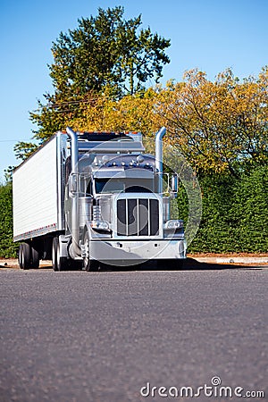 Classic powerful stylish American big rig semi truck with refrigeration semi trailer waiting for delivery route on truck stop par Stock Photo