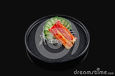 Classic raw crab sashimi with cucumber and daikon radish on a stylish black ceramic plate on a black background. Japanese Stock Photo