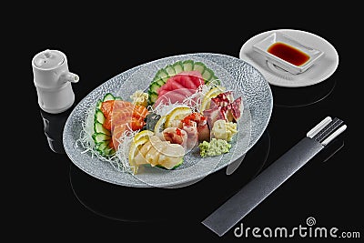 Classic raw set of sashimi octopus, salmon, sea bass, tuna, scallop with cucumber and daicon on grey ceramic plate on a black Stock Photo