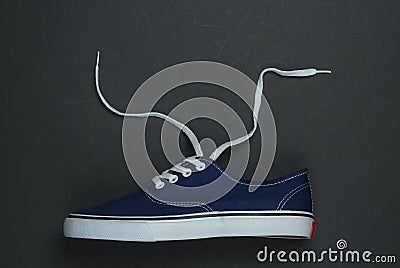 Classic retro sneaker with untied shoelaces.on a black background. Top view. Crop photo Stock Photo