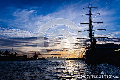 A classic sailboat moored to port in a beautiful sunset Stock Photo