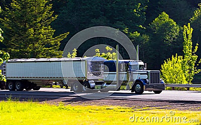 Classic semi truck big rig with two trailers on highway Stock Photo