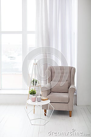 Classic soft armchair near the window in a room. Stock Photo