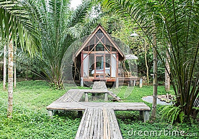 Classic Style Wooden House in The Cottage with The Wooden Path in front of The House surrounded by Nature View Various Trees Stock Photo