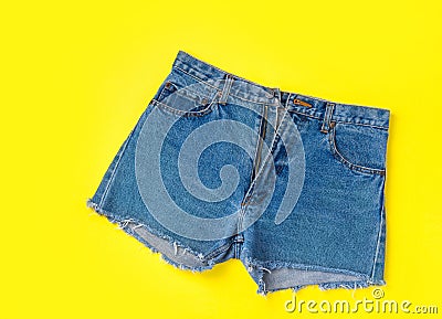 Classic Trendy Women Jeans Denim Shorts with Fringes on Bright Yellow Background. Flat Lay. Street Summer Fashion Sale Lifestyle Stock Photo