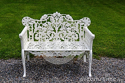 A classic white cast iron two-seater bench with oak leaf design throughout and attractive scrollwork on the seat, standing on a Stock Photo