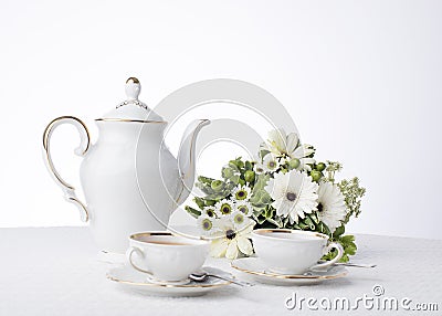 Classic white tea set with bouquet of white flowers and greenery on a white tablecloth Stock Photo