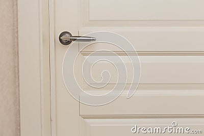 Classic white wooden milled door with chrome handle. White Scandinavian interior Stock Photo