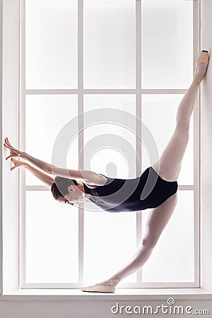 Classical Ballet dancer in split, ballerina at window sill Stock Photo