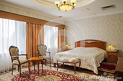 Classical bedroom with a large double bed, bedside tables, chairs Stock Photo