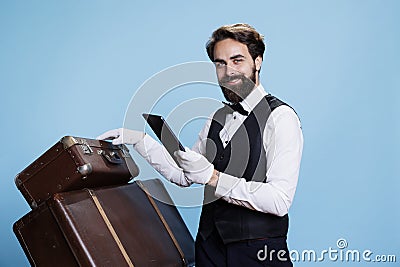 Classy doorman reads bookings on tablet Stock Photo