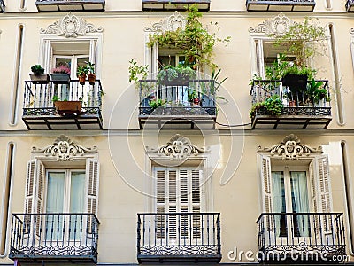 Classy old fashioned balconies decorated with ornamental stucco and vivid greenery downtown Madrid, Spain. Beautiful classical Stock Photo