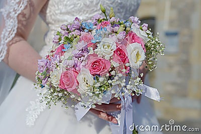 Classy young bride at the wedding ceremony with focus on the hand holding a floral arrangement Stock Photo