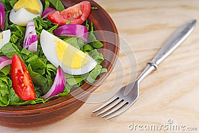 Clay bowl with salad spinach, egg,onion, tomatoes Stock Photo