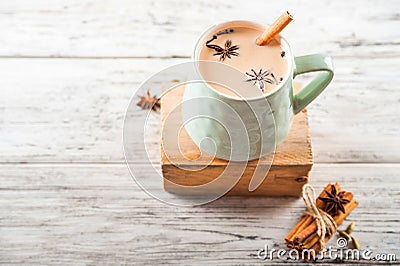 Clay cup on a wooden board on a light wooden table. A cup of masala tea. Spices cloves, fennel, cinnamon, cardamom, milk Stock Photo
