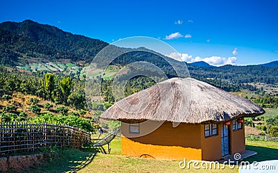 Clay house with a straw roof on the background of the mountains in the city of Pai in the north of Thailand. Asia travel Stock Photo