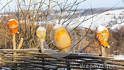 Clay jugs on wooden fence in winter Stock Photo