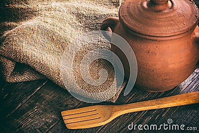 Clay pan on a wooden table. Wooden spoon and sacking Stock Photo