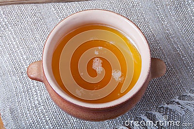 Clay pot with ghee and spoon on linen napkin. Rustic still life. Stock Photo