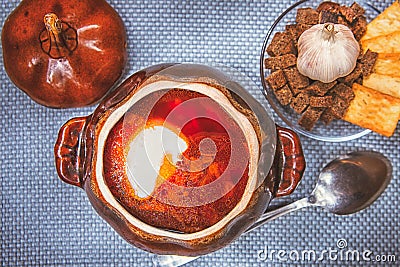 Clay pot with red soup and sour cream on a linen napkin Stock Photo