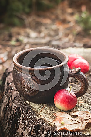 Clay Rural Cup with Hot Beverage and red apples on Wooden Stub. Stock Photo