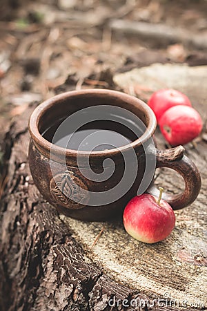 Clay Rural Cup with Hot Beverage and red apples on Wooden Stub. Stock Photo