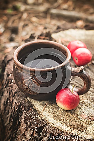 Clay Rural Cup with Hot Beverage and red apples on Wooden Stub. Stock Photo