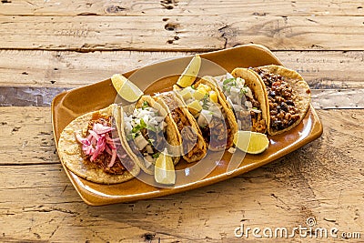 Clay tray with assorted Mexican tacos of cochinita pibil, pastor tacos, lime, Stock Photo