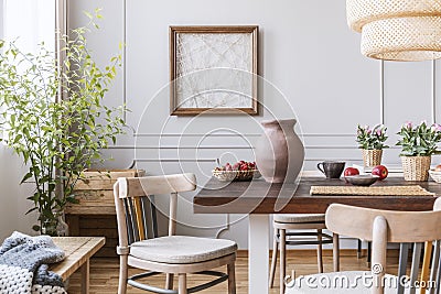 Clay vase on the table in a dining room interior with a plant, chairs and art on a wall Stock Photo