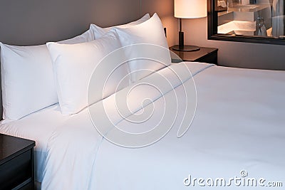 Clean Bedding sheets and pillow on natural wall room background. White bedding and pillow in hotel room. White pillows on bed. Stock Photo
