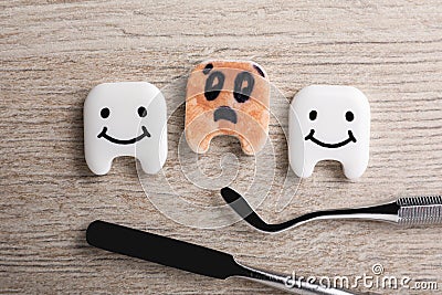 Clean and dirty plastic teeth with faces, dental tools on wooden table, flat lay Stock Photo