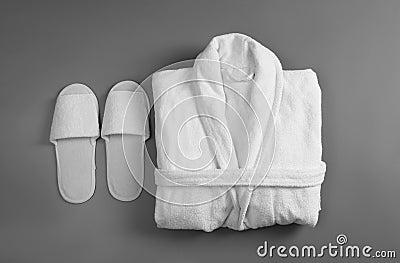 Clean folded bathrobe and slippers on grey background Stock Photo