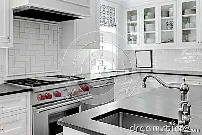 Luxury White Modern Kitchen Interior with White Cabinets with Gas Stove and Black Stone Counters Stock Photo