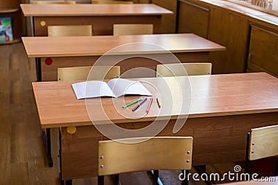 Clean notebook and colored pencils on the desk in empty classroom. Concept of school education Stock Photo