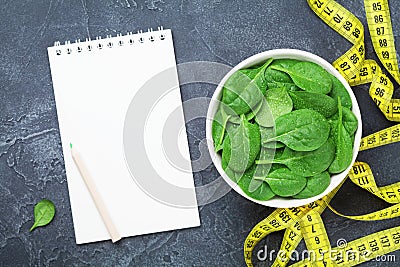 Clean notebook, green spinach leaves and tape measure top view. Diet and healthy food concept. Stock Photo