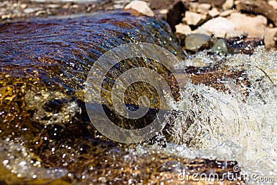 Clean river water flows over the stones and envelops them Stock Photo
