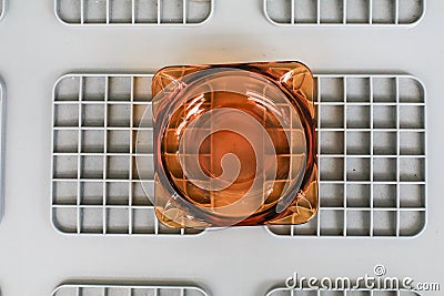 Clean round glass ashtray on grey plastic box. The concept of the harm of smoking. Stock Photo