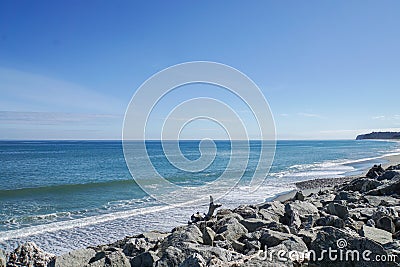 Sea wave and breeze at rock shore in New Zealand with bright blue sky Stock Photo