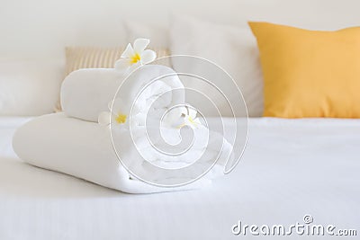 Clean white spa towels and flowers in blurred bedroom interior Stock Photo