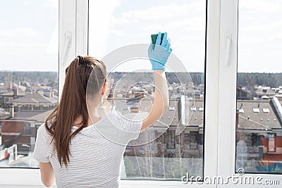 Cleaning of apartments, offices, cottages, warehouses, garages. Young girl with cleaning products sponges a window Stock Photo