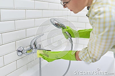 Cleaning the bathroom, woman washing tile wall and mixer with washcloth with detergent Stock Photo