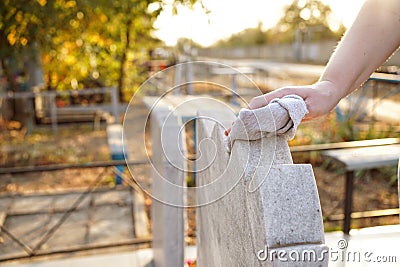 Cleaning cemetery. A woman`s hand washes grey monument at grave with rag. Stock Photo