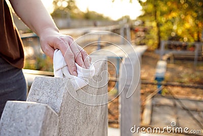 Cleaning cemetery. A woman`s hand washes grey monument at grave with rag. Stock Photo