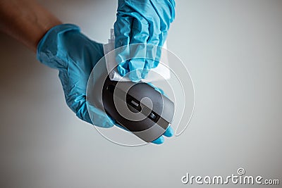 Cleaning a computer mouse device with a disposable antibacterial wipe during coronavirus pandemic emergency using hand sanitizer. Stock Photo